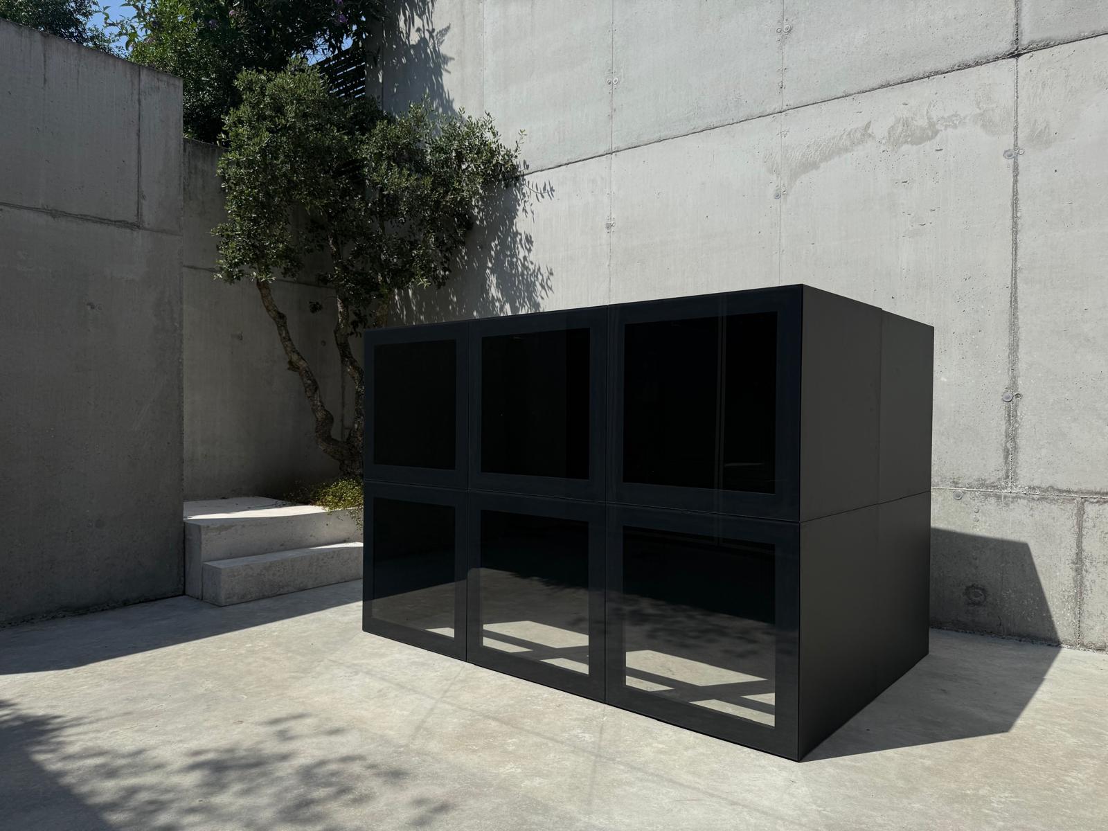 RO. glass-front module · three-by-two configuration, brushed aluminium and dark glass against concrete